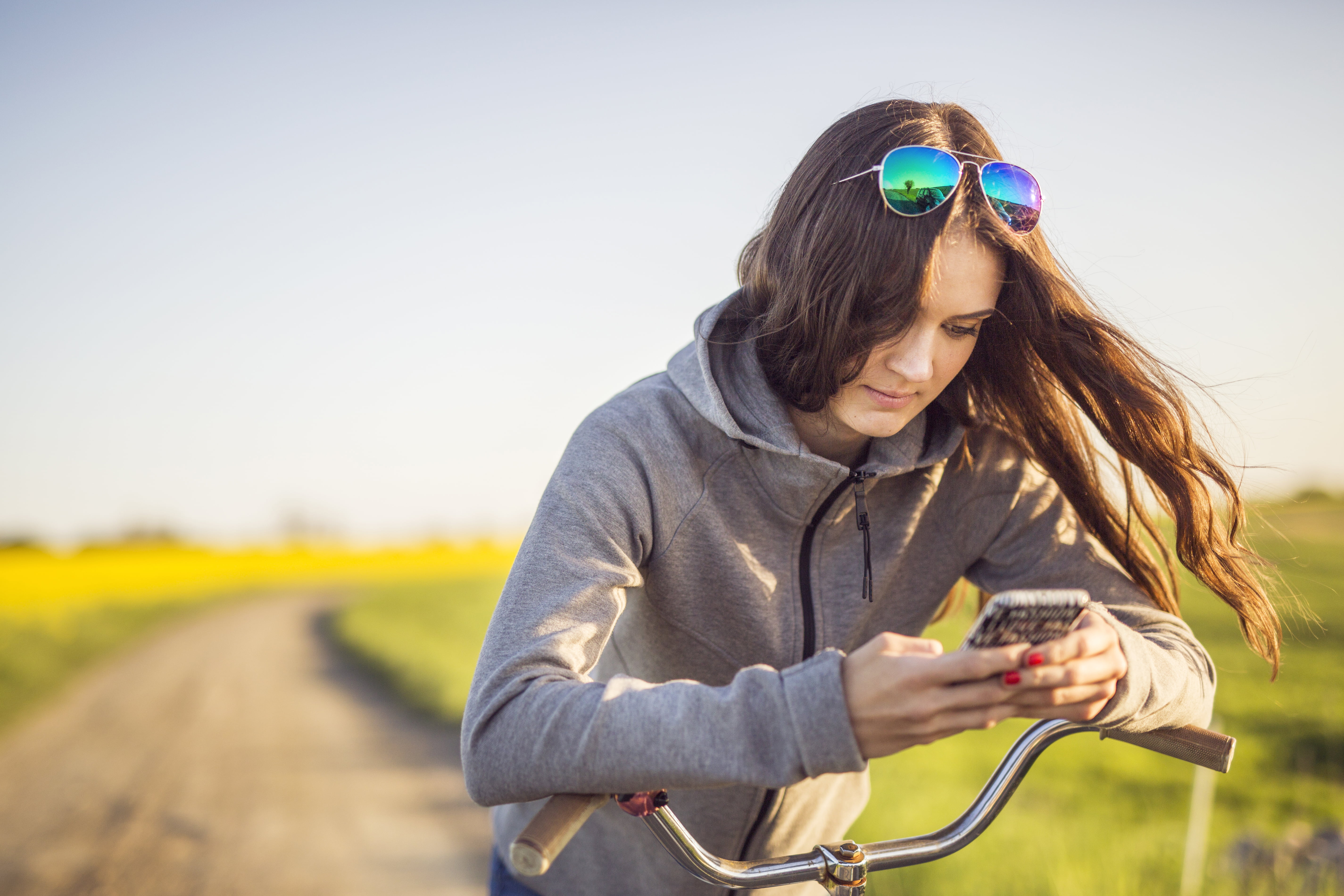 Ung dame med sykkel som har stoppet og taser på mobilen