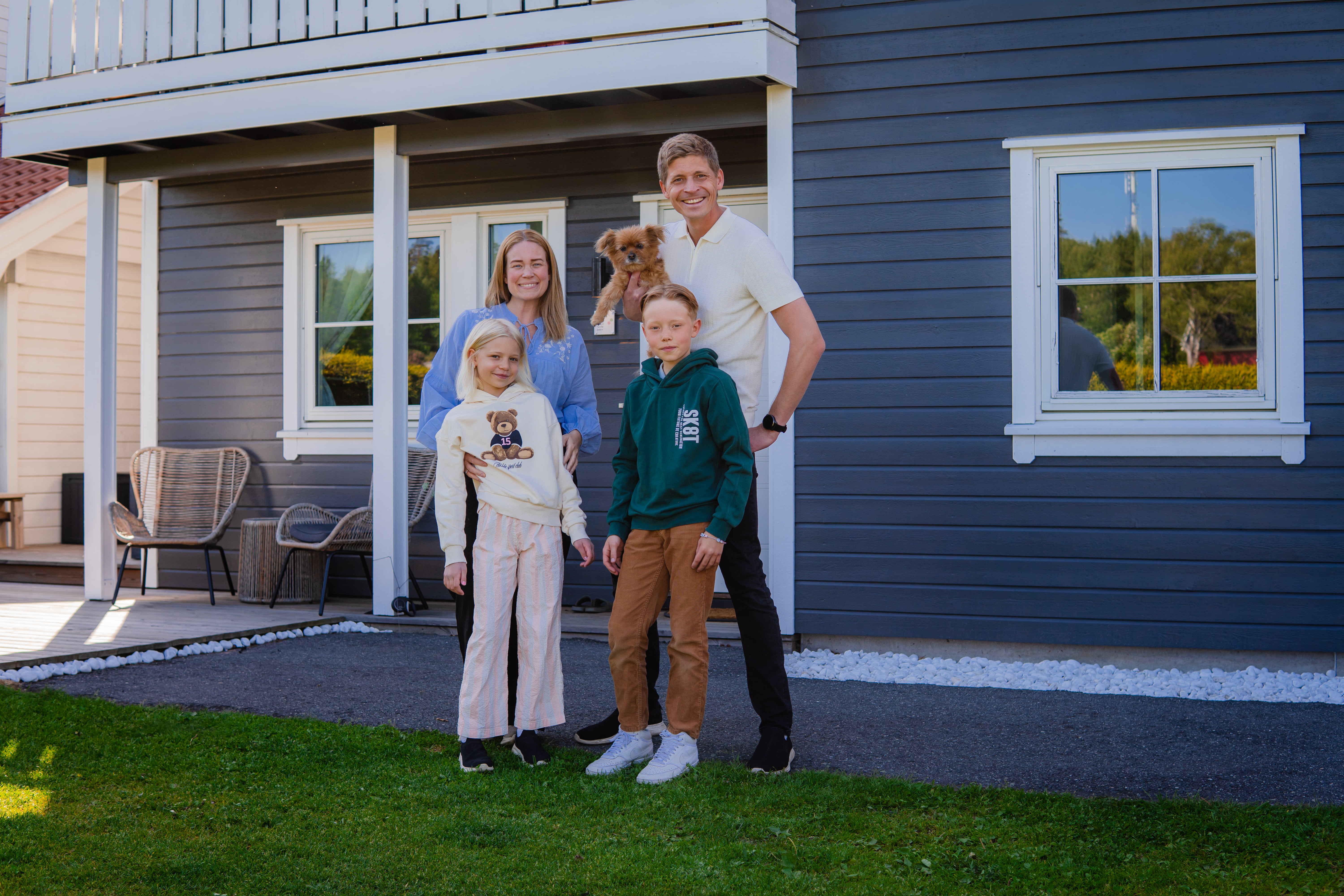 En familie med mor, far, sønn og datter står foran en enebolig.