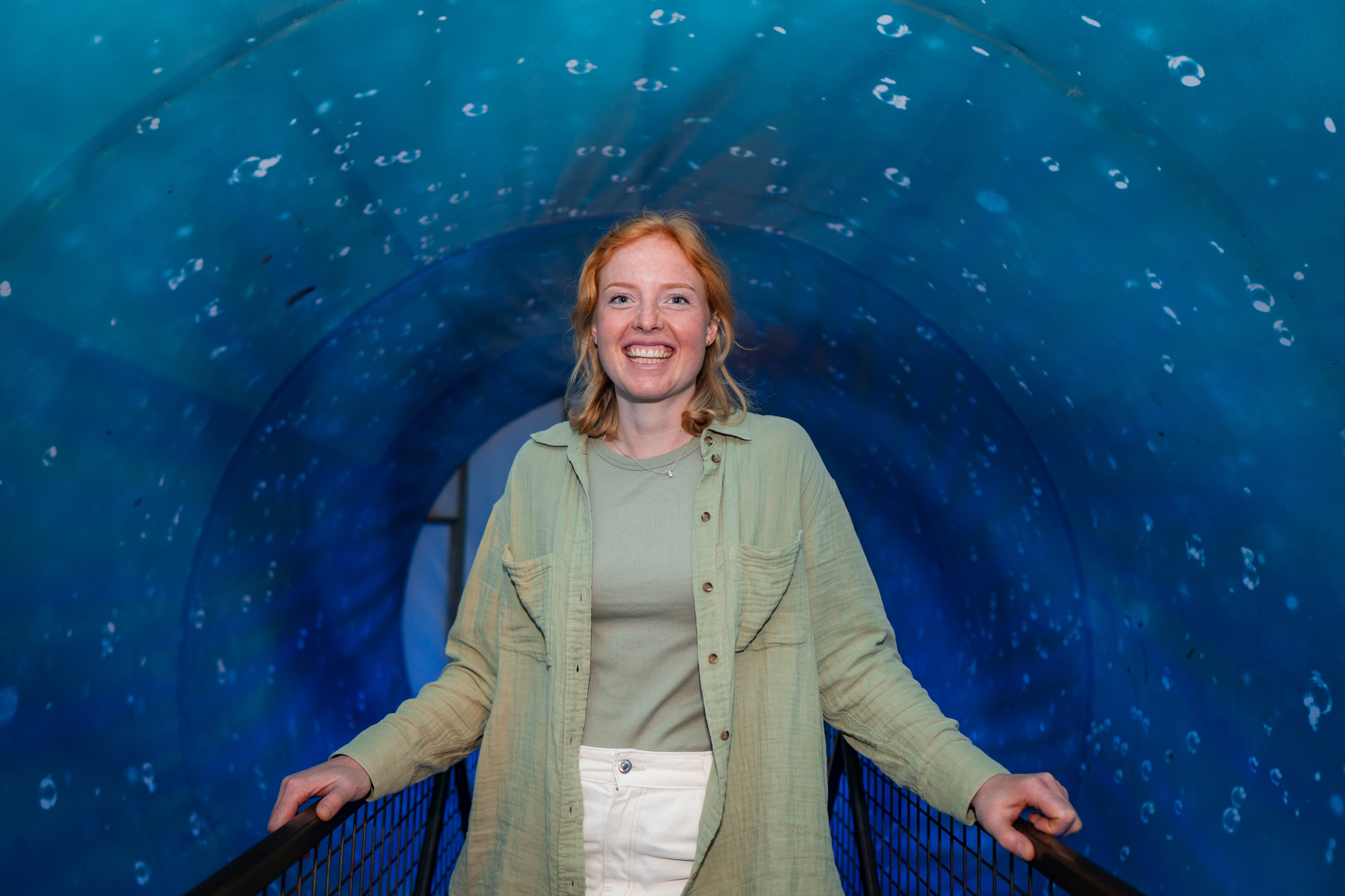 Portrett av en ung, smilende kvinne i blå omgivelser.