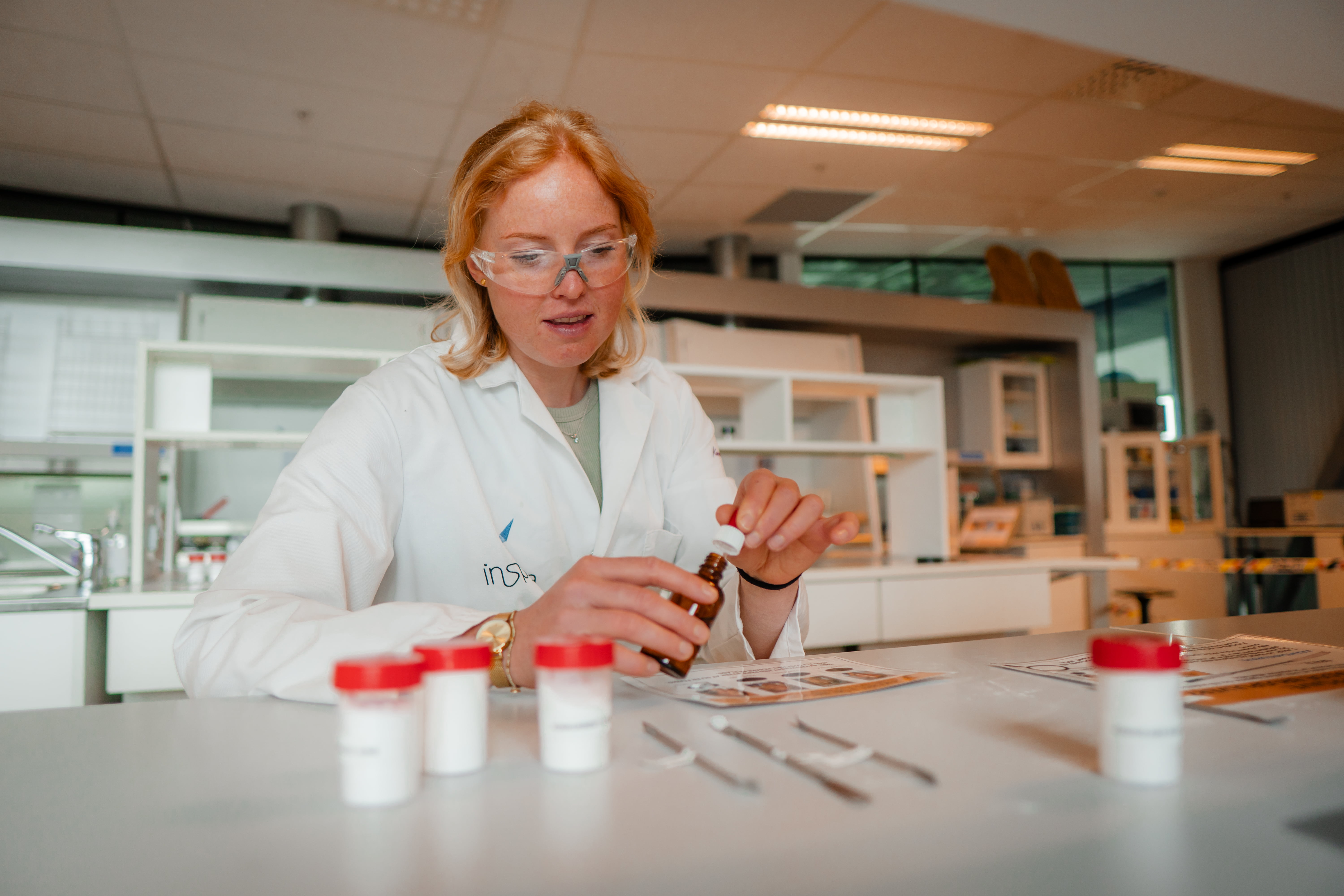 En ung kvinne iført hvit frakk jobber på et laboratorium.