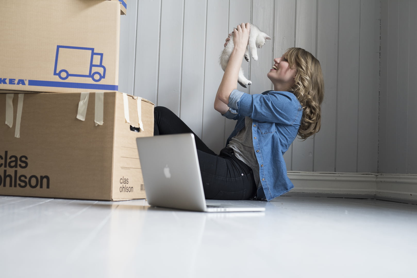 Dame holder katt  med flytte esker på gulvet. foto